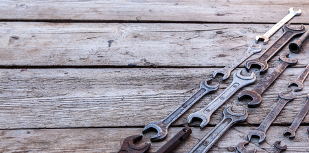 Metal wrench rusty tools lying on a black wooden table. Hammer, chisel, hacksaw, metal wrench. Copy space.の写真素材