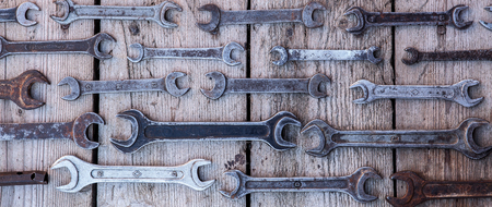 Metal wrench rusty tools lying on a black wooden table. Hammer, chisel, hacksaw, metal wrench. Dirty set of hand tools on a wooden panel vintage background with a tools.の写真素材