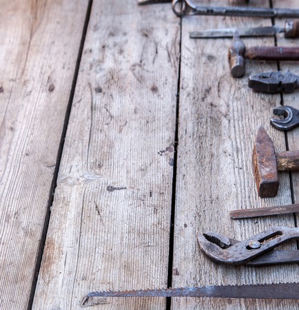Old, rusty tools lying on a black wooden table. Hammer, chisel, hacksaw, metal wrench. Copy spaceの写真素材