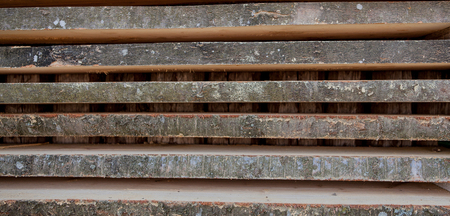 Folded wooden brown and gray planks in a sawmill. Piled alder boards as texture.の写真素材