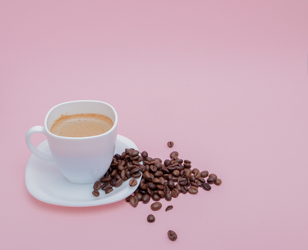 grains of roasted coffee scattered from a cup on a pink background, copy space.の写真素材