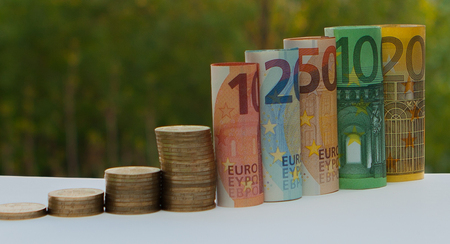 Ten, twenty, fifty, one hundred, two hundred and coins euro rolled bills banknotes on green blurred bokeh background. Histogram from the euro. Concept of currency growth, savings.の写真素材