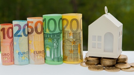 View Of coin stack with house model on green background, savings plans for housing, financial concept,Mortgage loading real estate property with loan money bank concept.Property Tax Concept.の写真素材