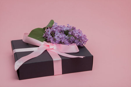 Gift box with pink ribbon on the pink background, decorated with lilac. Mother's Day. Birthday Valentine's Day. Copy space.の写真素材