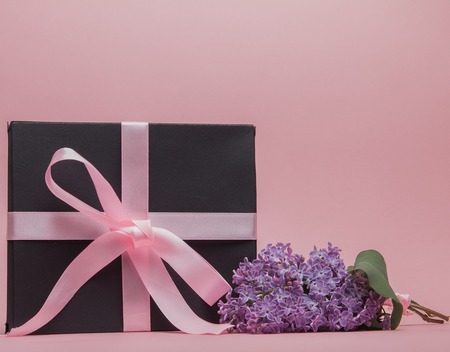 Gift box with pink ribbon on the pink background, decorated with lilac. Mother's Day. Birthday Valentine's Day. Copy space.の写真素材