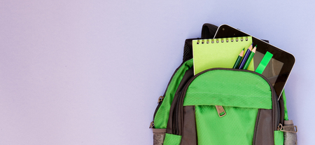 Backpack with school supplies on violet backgriond.の写真素材
