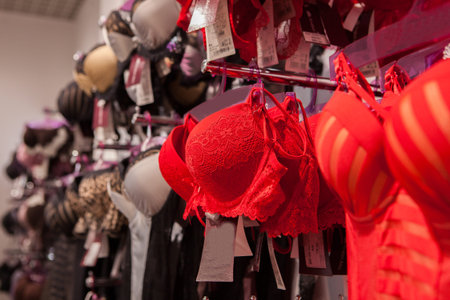 Red lace bra hanging on rack in underwear store. Toned with selective focus.の写真素材