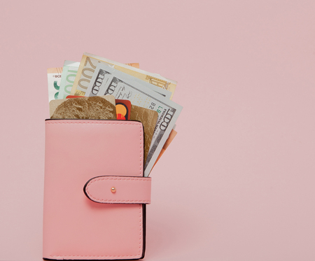 Bank cards, dollars and euro in a pink wallet on the pink background with copy space.の写真素材
