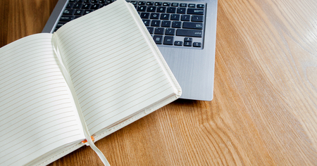 Notepad, laptop on old wooden desk. View from above with copy space in vintage tone.の写真素材