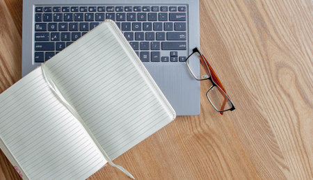 Notepad, Laptop and Glasses on old wooden desk. View from above with copy space in vintage tone.