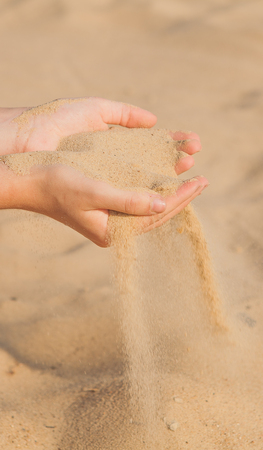 Sand flowing through the woman's hands on the beach.の写真素材