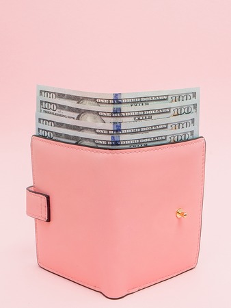 Purse with one hundred dollars banknotes on pink background. Flat lay, top view, copy space.の写真素材
