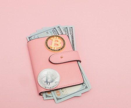 Bitcoin and dollars in a pink wallet on the pink background with copy space.の写真素材