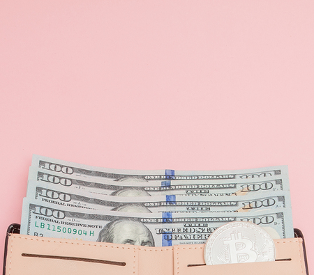Bitcoin and dollars in a pink wallet on the pink background with copy space.の写真素材