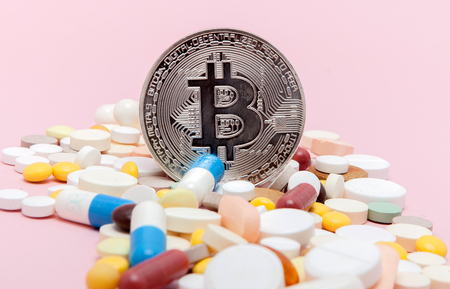Bitcoin and pills on a pink background. Bitcoin as a medicine for the economy. Cryptocurrency bitcoin as a payment option for medicines.の写真素材
