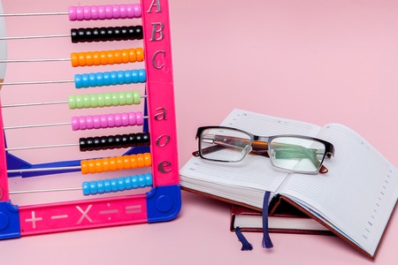 Colored Abacus, Glasses and Notebook on pink background. Education, back to school concept.の写真素材