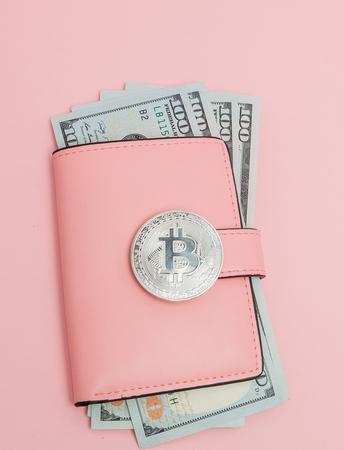 Bitcoin and dollars in a pink wallet on the pink backgroundの写真素材