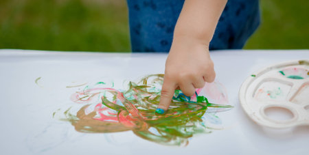 Cute little boy painting with a paint hands using gauche paints.の写真素材
