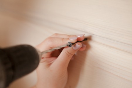 Close-up the woman holding the screw and the electric screw-driver.の写真素材