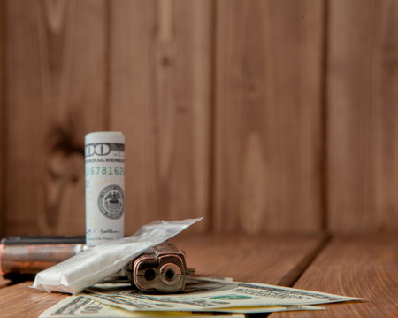 Stack of Money, drugsand a gun on a wooden table, concept about danger and threat of the drug, copy...