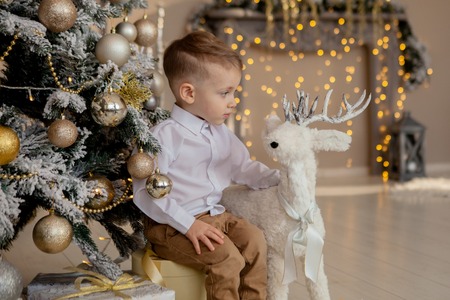 happy boy laying on floor with christmas gifts in decorated room.の写真素材