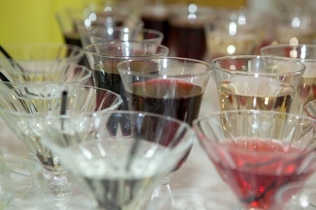 Beautiful row line of different colored alcohol cocktails on a party, martini, vodka,and others on decorated catering bouquet table on open air event, picture with beautiful bokeh.の写真素材