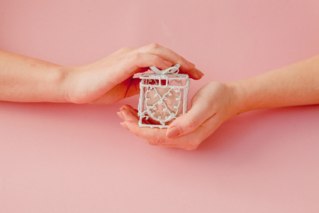 Woman's hands holding bitcoin in pink gift box on a pink background, symbol of virtual money.の写真素材
