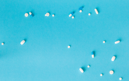 Assorted pharmaceutical medicine pills, tablets and capsules over blue background.の写真素材