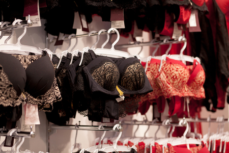 Advertise, Sale, Fashion concept - Close up of womans hand choosing underwear on hangers in the supermarketの写真素材