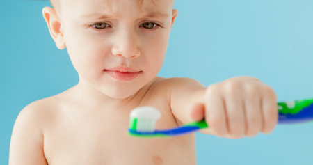 Portrait of little boy with toothbrush on blue background.の写真素材