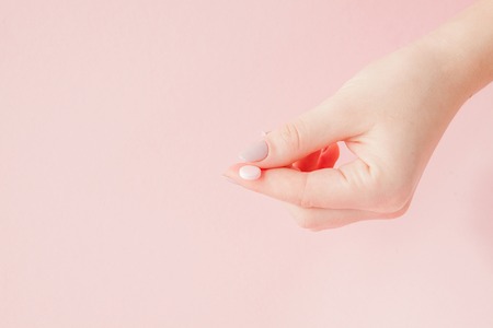 Pink pills tablets in the woman hand on pink background. Top view. Flat lay. Copy space. Medicine concept.の写真素材