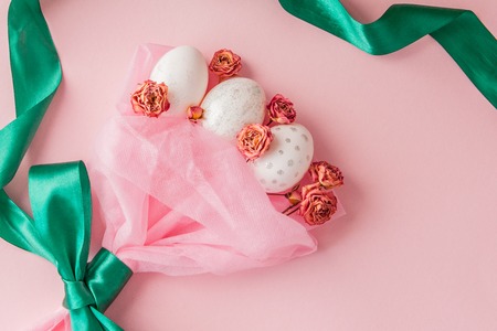 White Easter eggs in a bouquet with a green ribbon on pink background.の写真素材