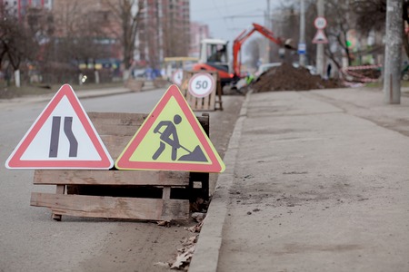 Road signs, detour, road repair on street background, truck and excavator digging hole.の写真素材
