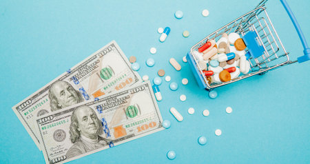 Dollars, pills and shopping cart on a blue background. Pharmacy concept. Copy space.