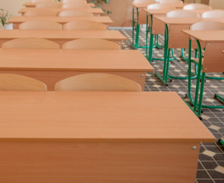 Interior of empty classroom with chairs and desks in a row.