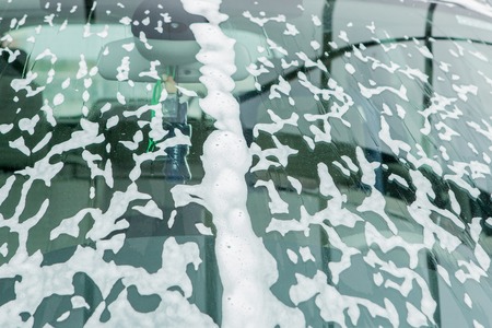 White foam and soap on dark background. Abstract pattern. The concept of washing oily pan or black car.の写真素材