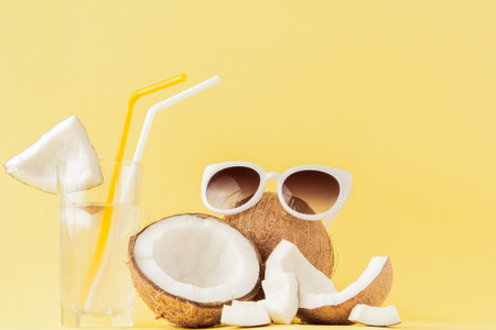 Fresh Coconut cocktail with a straws on yellow background.