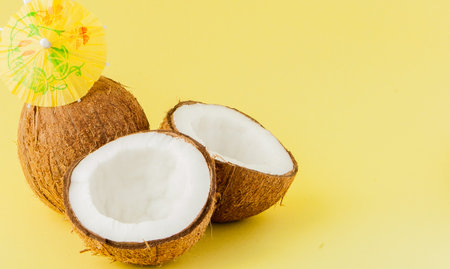 Fresh Coconut cocktail with a straws on yellow background, copy space.