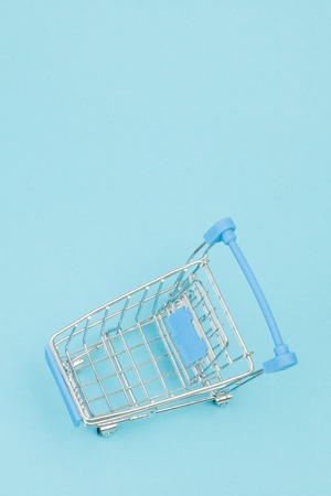 Tiny shopping cart on the blue background with space for text.の写真素材
