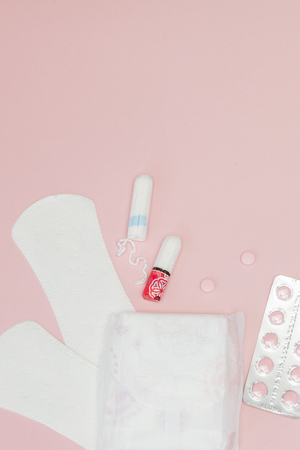 Sanitary pads and tampons and pills on pink background. Woman critical days, gynecological menstruation cycle. Menstruation sanitary woman hygiene. Medical concept.Top view, flat lay, copy space.の写真素材