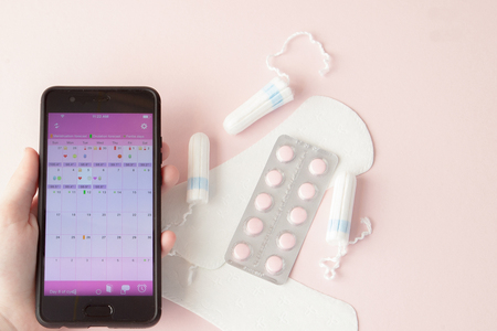 Tampon, feminine, sanitary pads for critical days, feminine calendar, pain pills during menstruation on a pink background. Tracking the menstrual cycle and ovulation.の写真素材