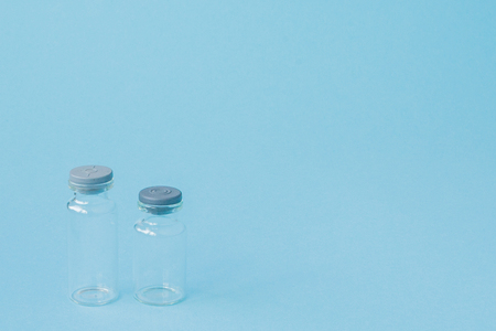 Vial of medicine on blue background with copy space. Antibiotic or vaccine medication. Healthcare and pharmacy innovations.の写真素材