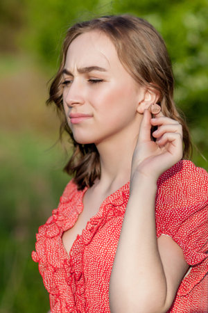 Close-up Of Female Hands Putting Hearing Aid In Ear. Modern digital in the ear hearing aid for...