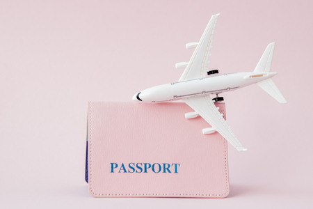 Passport and plane on a pink background. Travel concept, copy space.の写真素材