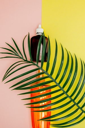 Bottle sunblock on bright square yellow and pink background. The concept of the resort at sea, summer time. Top view, flat lay, minimalism, copy space.の写真素材