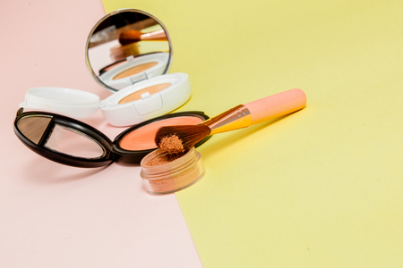 Make up products spilling on to a bright yellow and pink background with copy space, minimal styleの写真素材