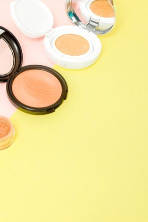 Make up products spilling on to a bright yellow and pink background with copy space, minimal styleの写真素材