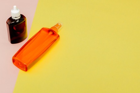 Bottle sunblock on bright square yellow and pink background. The concept of the resort at sea, summer time. Top view, flat lay, minimalism, copy space.の写真素材