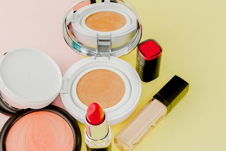 Make up products spilling on to a bright yellow and pink background with copy space, minimal styleの写真素材