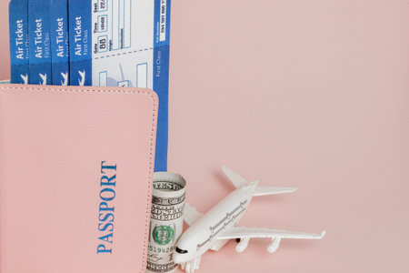 Passport, dollars, plane and air ticket on a pink background. Travel concept, copy space.